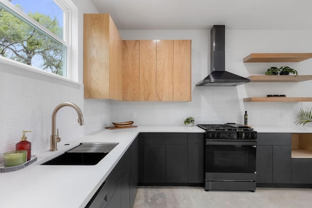 kitchen featuring sink, gas stove, decorative backsplash, and wall chimney range hood