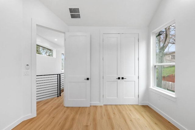 unfurnished bedroom featuring multiple windows, light hardwood / wood-style floors, and a closet