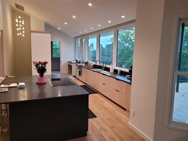 kitchen with black electric cooktop, lofted ceiling, sink, and a kitchen island