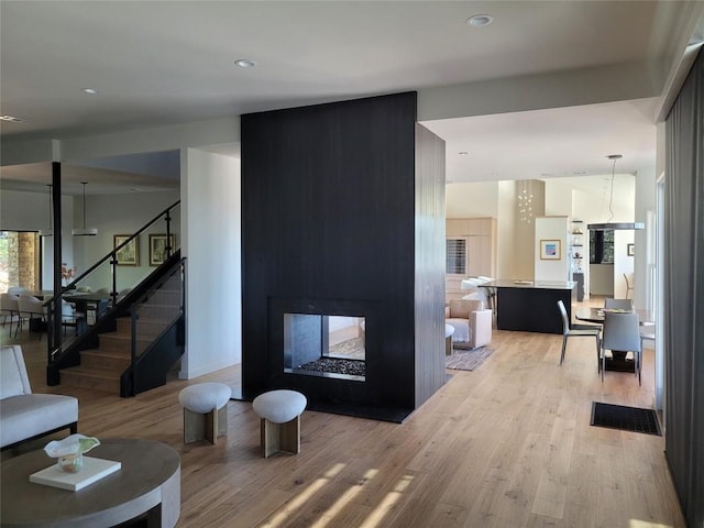 living room with light wood-type flooring and a multi sided fireplace