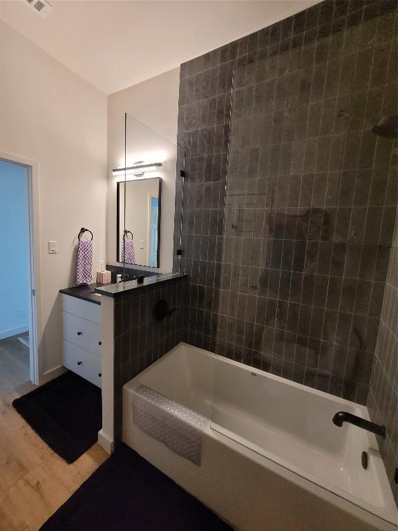 bathroom featuring hardwood / wood-style flooring, vanity, and tiled shower / bath combo