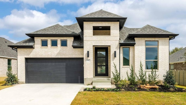 view of front of house with driveway, roof with shingles, a front lawn, and brick siding