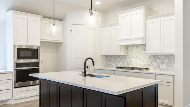 kitchen featuring hanging light fixtures, white cabinets, stainless steel appliances, and light countertops