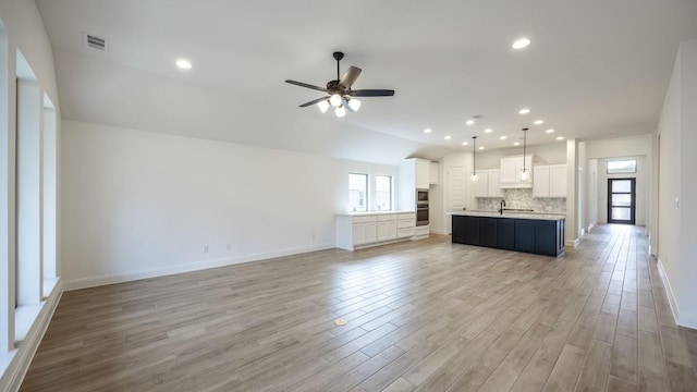 unfurnished living room with ceiling fan, visible vents, light wood-style flooring, and baseboards