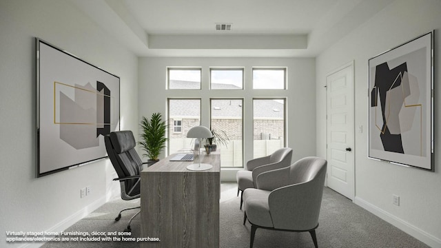 office space with baseboards, a raised ceiling, visible vents, and light colored carpet