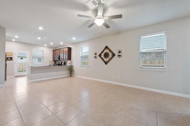 interior space with ceiling fan, kitchen peninsula, and light tile patterned floors