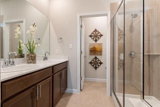 full bath featuring double vanity, a stall shower, and a sink