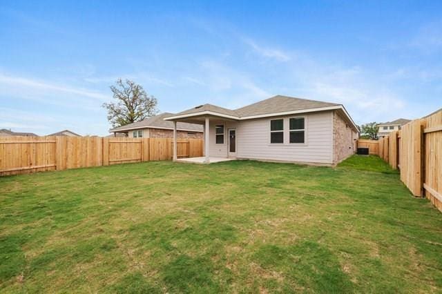 rear view of house with a patio area, a fenced backyard, and a lawn