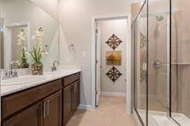 bathroom featuring double vanity, a stall shower, and a sink