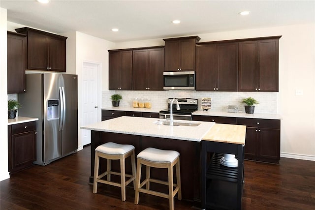 kitchen with tasteful backsplash, sink, a center island with sink, and appliances with stainless steel finishes