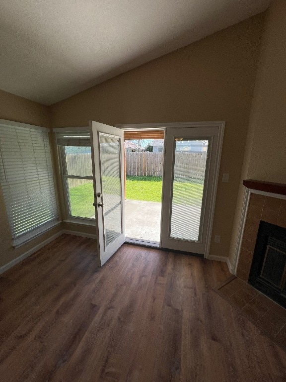 doorway with a fireplace, dark wood-type flooring, and vaulted ceiling