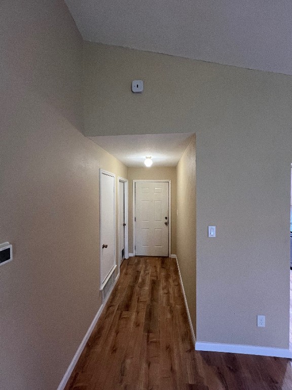 corridor with lofted ceiling and dark hardwood / wood-style floors