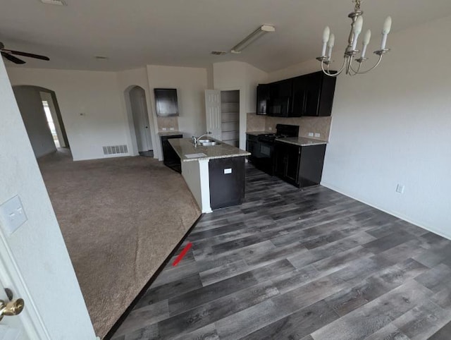 kitchen featuring sink, ceiling fan with notable chandelier, dark hardwood / wood-style floors, an island with sink, and black range with gas stovetop