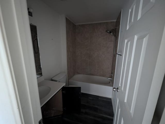 full bathroom featuring vanity, tiled shower / bath, hardwood / wood-style flooring, and toilet