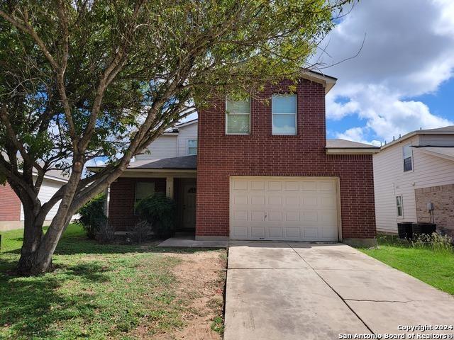 view of property with a garage, a front yard, and central air condition unit