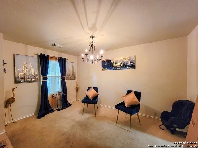 sitting room with carpet and a notable chandelier