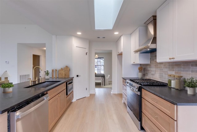 kitchen featuring light brown cabinetry, a skylight, sink, white cabinets, and stainless steel appliances