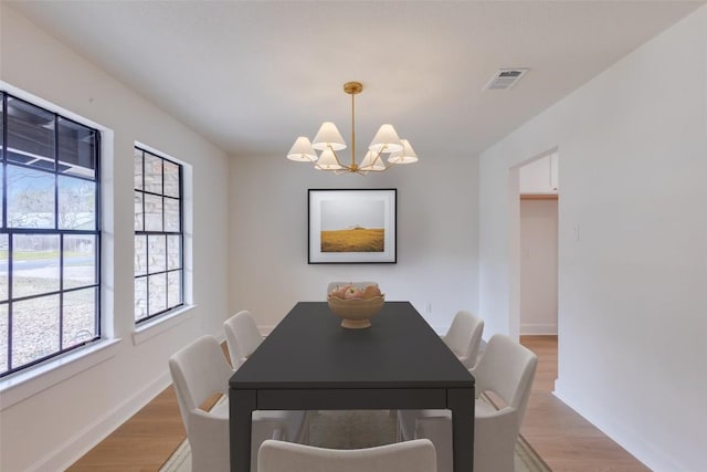 dining area with light hardwood / wood-style flooring and a chandelier