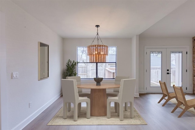 dining room with a notable chandelier, a wealth of natural light, french doors, and wood-type flooring