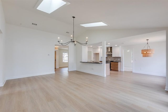 unfurnished living room with lofted ceiling with skylight, sink, an inviting chandelier, and light wood-type flooring