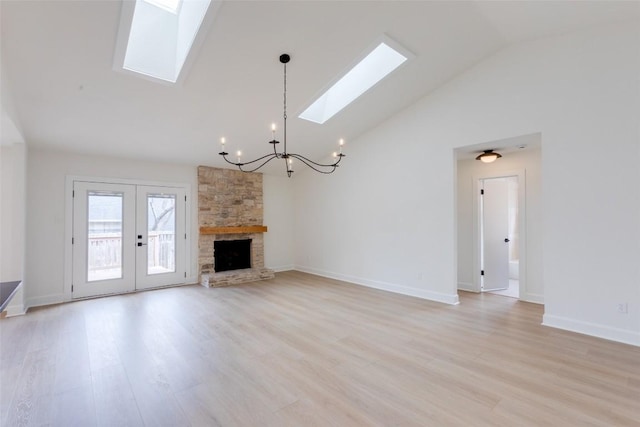 unfurnished living room with a skylight, high vaulted ceiling, light hardwood / wood-style flooring, a notable chandelier, and a fireplace