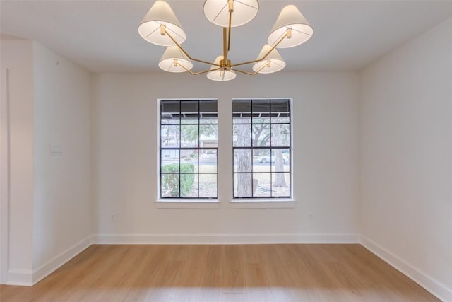 empty room featuring a notable chandelier and light hardwood / wood-style floors