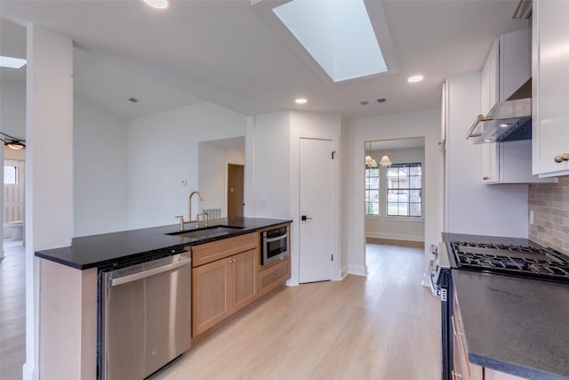 kitchen featuring sink, light brown cabinets, appliances with stainless steel finishes, decorative backsplash, and wall chimney range hood