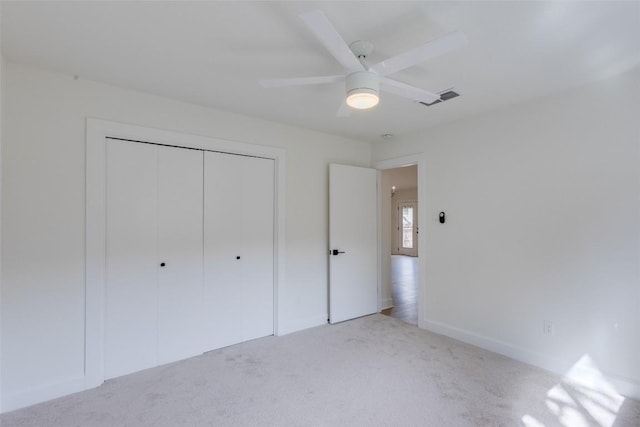 unfurnished bedroom featuring ceiling fan, light colored carpet, and a closet