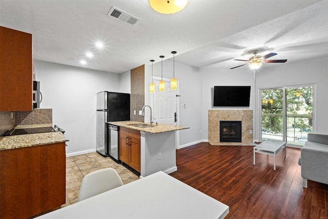 kitchen featuring a fireplace, decorative light fixtures, sink, kitchen peninsula, and stainless steel appliances