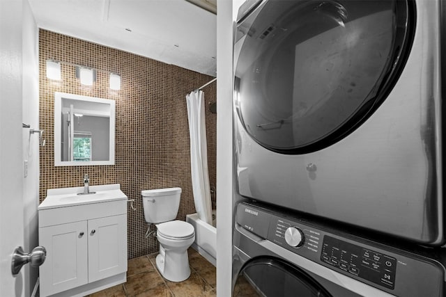 full bathroom with tile walls, stacked washer and dryer, vanity, toilet, and shower / bath combo with shower curtain