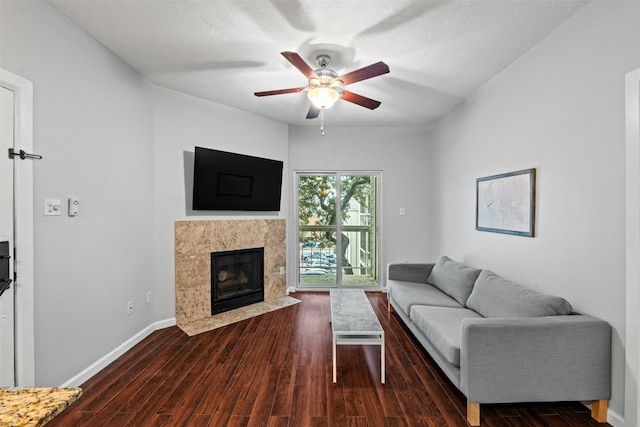 living room with dark wood-type flooring, ceiling fan, and a fireplace