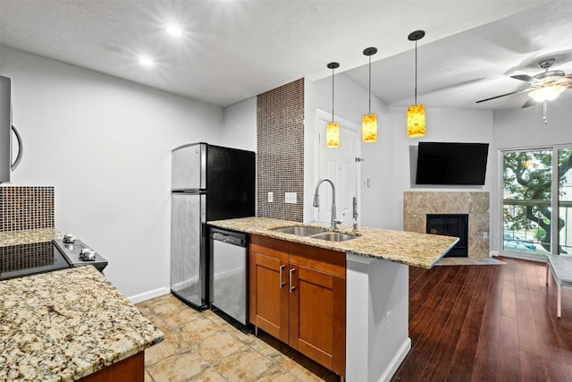 kitchen featuring pendant lighting, sink, light stone counters, stainless steel appliances, and a premium fireplace