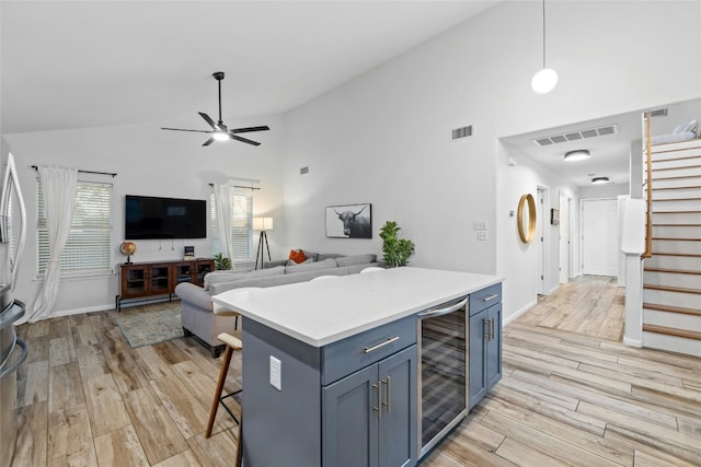 kitchen featuring pendant lighting, beverage cooler, a kitchen breakfast bar, a center island, and light wood-type flooring