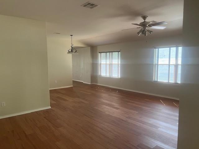 spare room with dark hardwood / wood-style flooring, a wealth of natural light, and ceiling fan