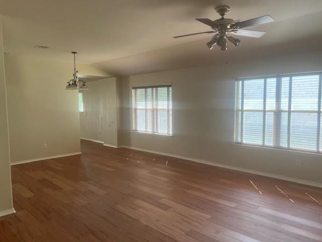 spare room featuring dark hardwood / wood-style flooring and ceiling fan with notable chandelier