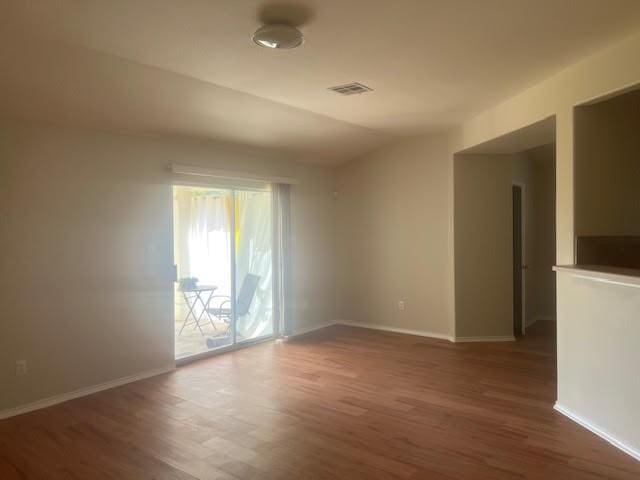 unfurnished room with dark hardwood / wood-style floors and vaulted ceiling