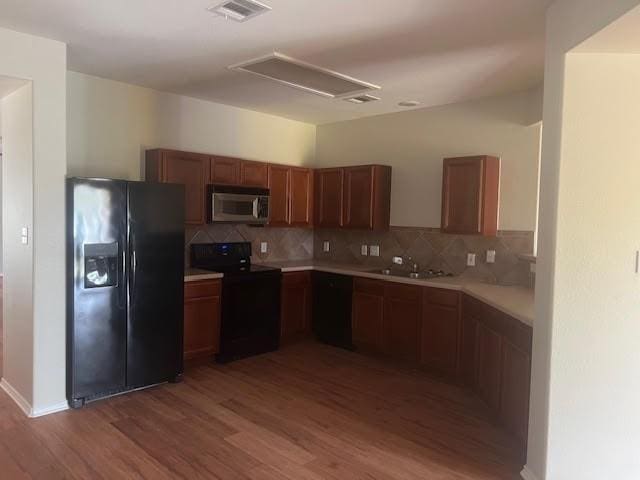 kitchen featuring backsplash, sink, hardwood / wood-style floors, and black appliances