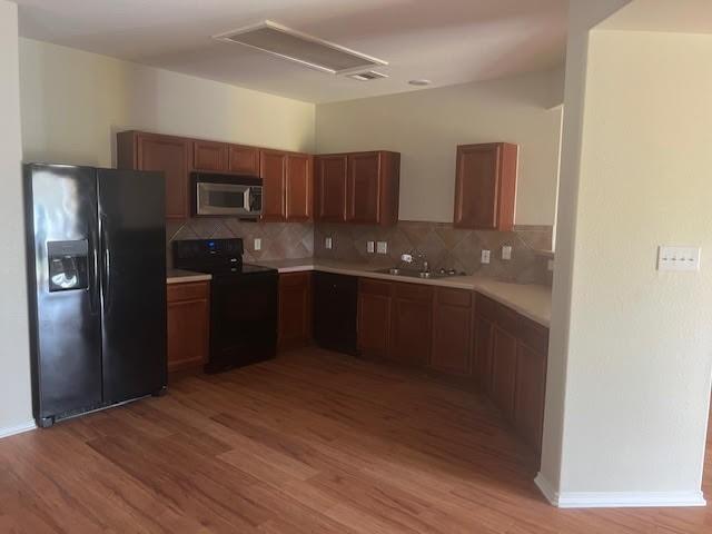 kitchen featuring sink, backsplash, black appliances, and light hardwood / wood-style floors