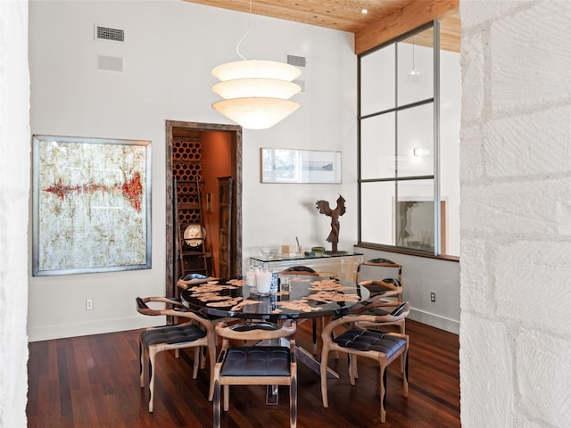 dining area featuring hardwood / wood-style floors, wood ceiling, beamed ceiling, and a towering ceiling