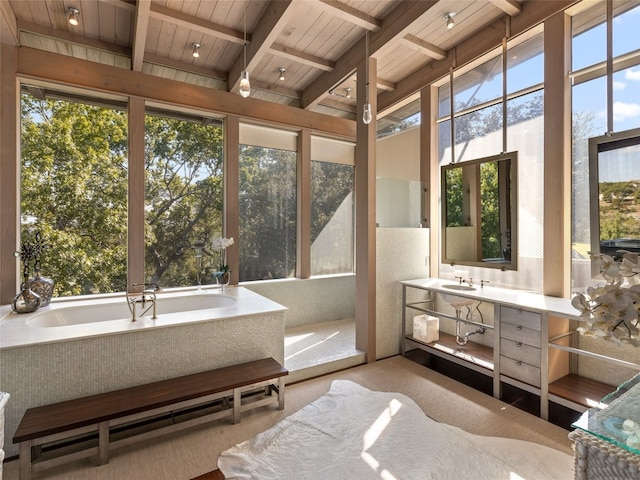 bathroom with beam ceiling, a bathtub, plenty of natural light, and wooden ceiling