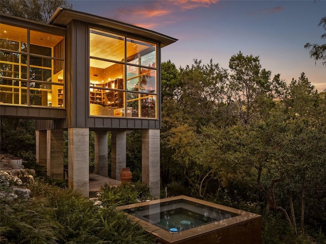 property exterior at dusk with an in ground hot tub and a patio