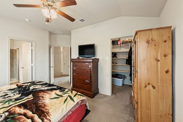 carpeted bedroom featuring lofted ceiling, a walk in closet, ensuite bath, a closet, and ceiling fan