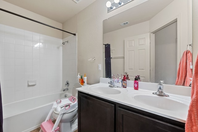 full bathroom with tiled shower / bath, vanity, and toilet