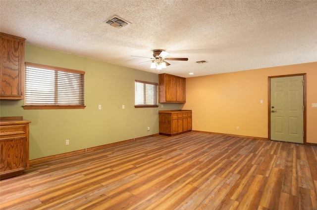 unfurnished living room with ceiling fan, a textured ceiling, and light wood-type flooring