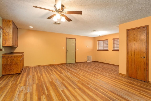 unfurnished living room featuring ceiling fan, light hardwood / wood-style floors, and a textured ceiling