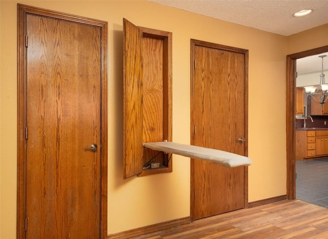 hall featuring sink, a textured ceiling, and light wood-type flooring