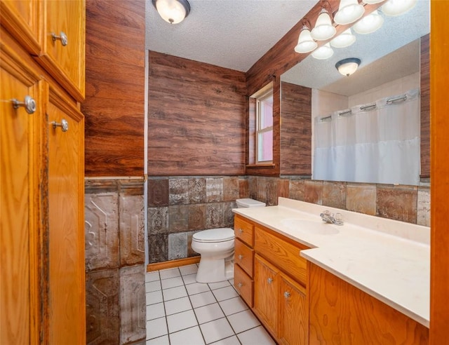 bathroom featuring tile patterned flooring, tile walls, vanity, a textured ceiling, and toilet