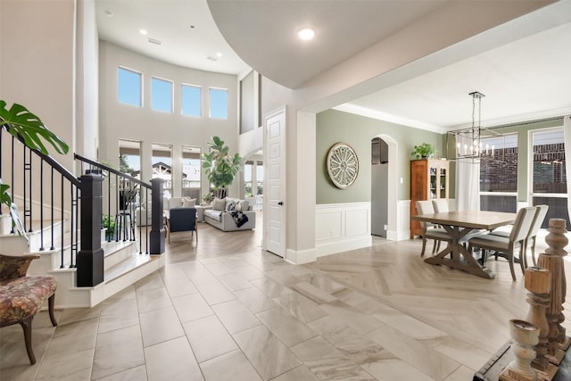 foyer featuring a towering ceiling, ornamental molding, and a chandelier