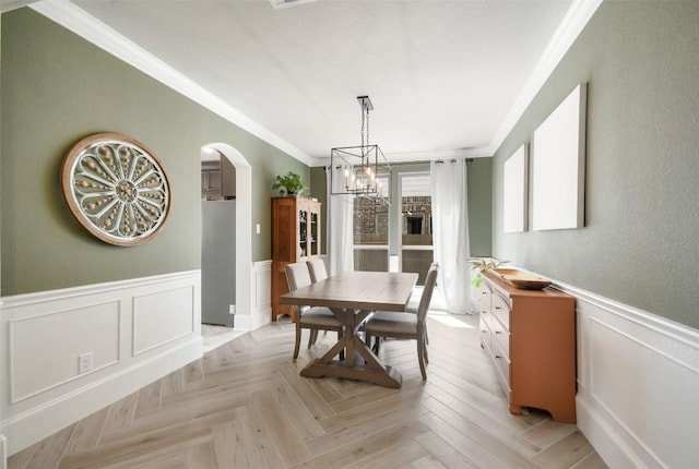 dining area featuring an inviting chandelier, crown molding, and light parquet floors