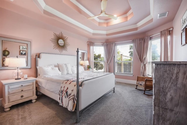 bedroom featuring multiple windows, crown molding, dark carpet, and a tray ceiling